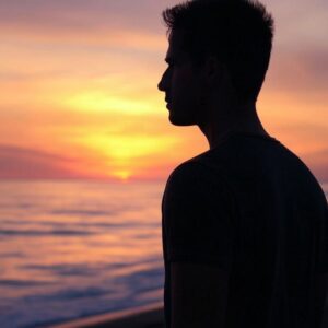 Silueta člověka u moře při západu slunce