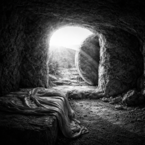 Čtvercová černobílá fotografie zachycuje prázdný Ježíšův hrob vytesaný do skály, jehož vstup je otevřen a osvětlen silným světlem přicházejícím zvenčí. V popředí leží na kamenném lůžku složené pohřební plátno, zatímco velký odvalený kámen stojí stranou u vchodu. Kontrast mezi temným vnitřkem hrobu a jasným světlem venku vytváří silný symbolický obraz vzkříšení, naděje a vítězství života nad smrtí.