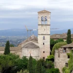 Kamenná bazilika s hranolovou zvonicí nad krajinou Assisi