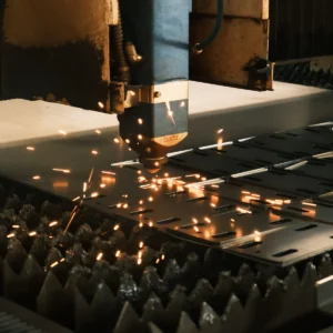 Průmyslový laser řeže tabuli materiálu a kolem místa řezu odlétají jiskry
