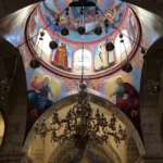 Malovaná chrámová kupole s biblickými postavami nad mohutným lustrem
