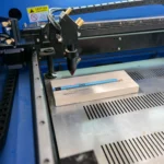 Otevřená laserová gravírka pracující na malém kusu světlého dřeva