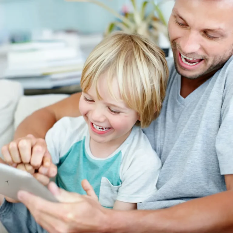 Otec se synem se smějí při společné hře na tabletu