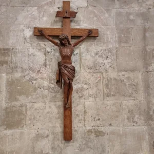 Dřevěný krucifix zavěšený na světlé kamenné stěně
