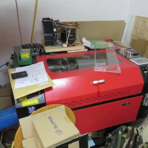 Červená uzavřená laserová řezačka obklopená dílenským vybavením