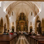 Pohled do katolického kostela na věřící v lavicích během mše