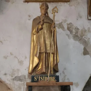 Zlatě zbarvená socha biskupa s berlou na kostelní zdi