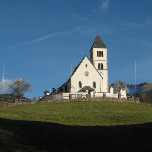 Bílý venkovský kostel svatého Wolfganga na travnatém návrší
