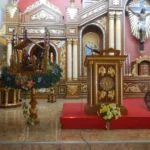 Kostelní interiér s adventním věncem, jesličkami a dřevěným ambonem
